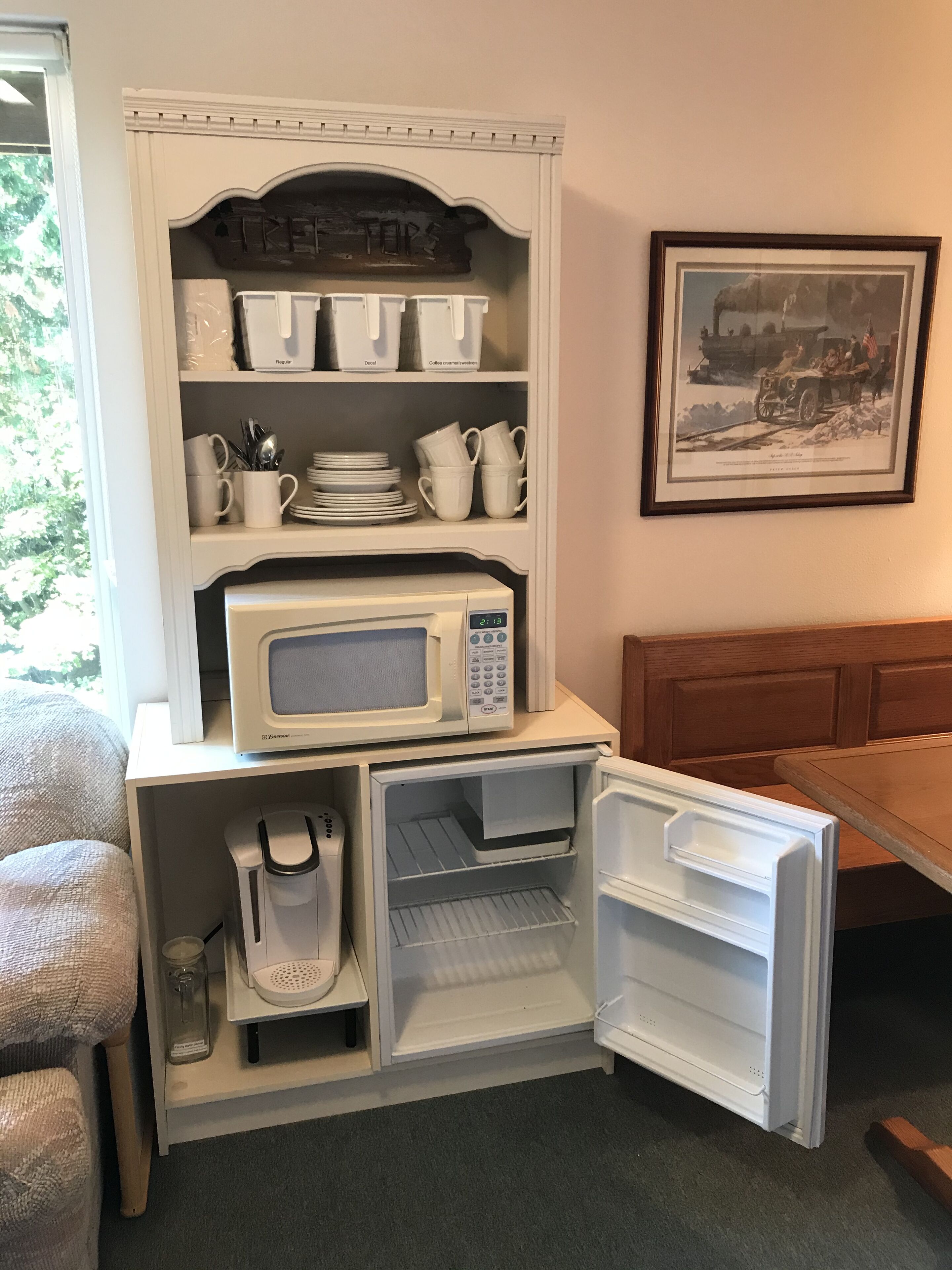 A compact kitchenette with a microwave, coffee maker, and storage shelves.