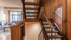 Eine Holztreppe mit Handlauf und Teppichstufen, die zu einer Zwischenebene führen.