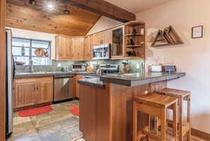 Cucina con mobili in legno, isola centrale, microonde, piano cottura e lavello.