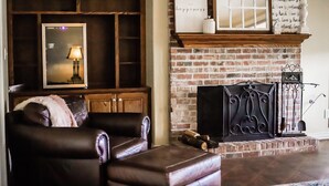 Ein gemütliches Wohnzimmer mit Ledersofa, Kamin und Backsteinwand.
