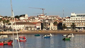 A coastal town with a marina, buildings with red roofs, and a hotel with a sign. - Fabulous Terrace 2 - Checkinhome (Cascais)