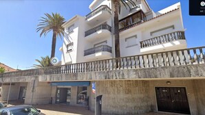 A multi-story building with balconies, a parking area, and a palm tree. - Fabulous Terrace 2 - Checkinhome (Cascais)