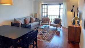 A living room with a sofa, chairs, a coffee table, a dining table, and a patterned rug. - Fabulous Terrace 2 - Checkinhome (Cascais)