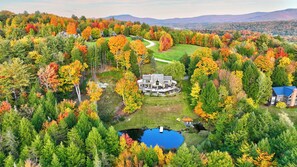 A large estate with a central house surrounded by a manicured lawn and a pond.