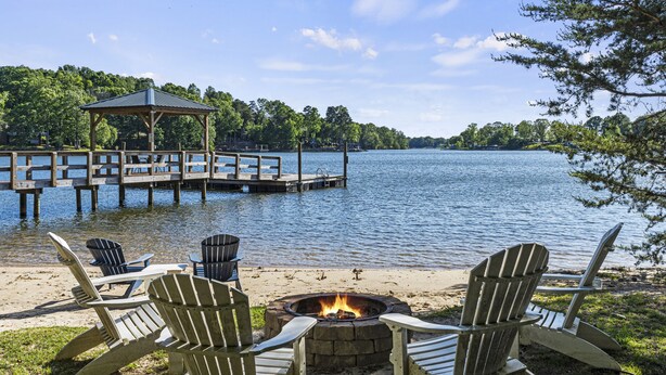 Terraza junto al lago con sillas Adirondack, una fogata y un pabellón.