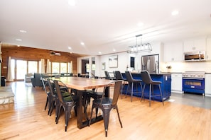 A spacious kitchen with a wooden dining table, modern appliances, and a blue island.