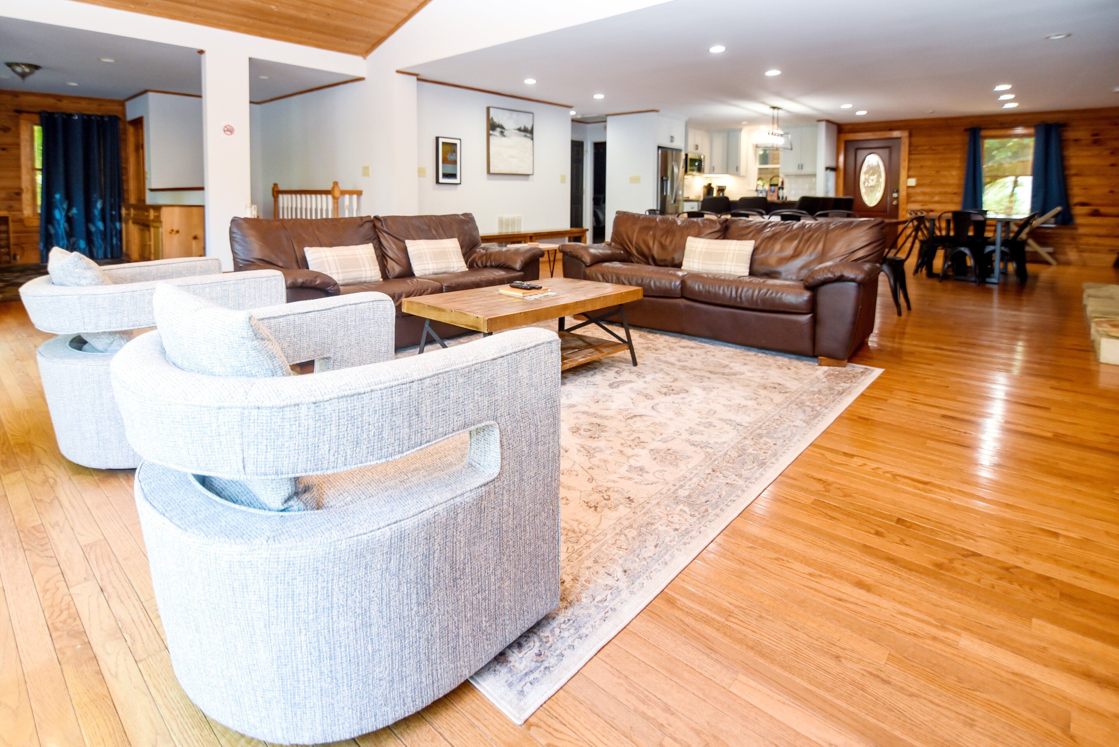 A spacious living room with leather sofas, a wooden coffee table, and a patterned rug.