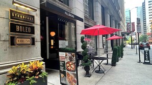 Ein Restaurant namens Steadfast Boleo mit Außenbereich und roten Sonnenschirmen.