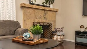 Un salon comprenant un canapé, une table basse avec un plateau, une cheminée et une table d’appoint agrémentée d’objets décoratifs.