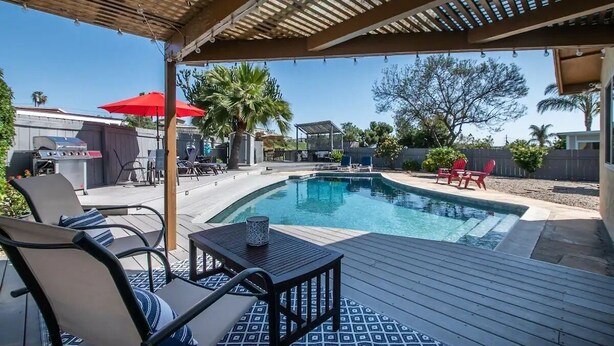 Un espace piscine agrémenté d’une pergola, de chaises longues et d’un barbecue.