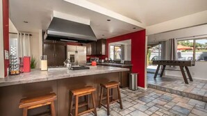 Une cuisine moderne dotée d’un îlot central, de tabourets de bar et offrant une vue sur l’extérieur.