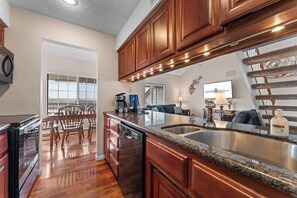 A modern kitchen with wooden cabinets, a granite countertop, and a built-in dishwasher.