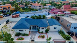 A residential area with a house featuring a blue roof, a front porch, and a driveway. - Newly Renovated 4BR 4BA Private Pool @ Eagle Beach (Noord)