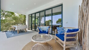 Un patio moderno al aire libre con mobiliario de mimbre, una mesa de comedor y vista al mar.