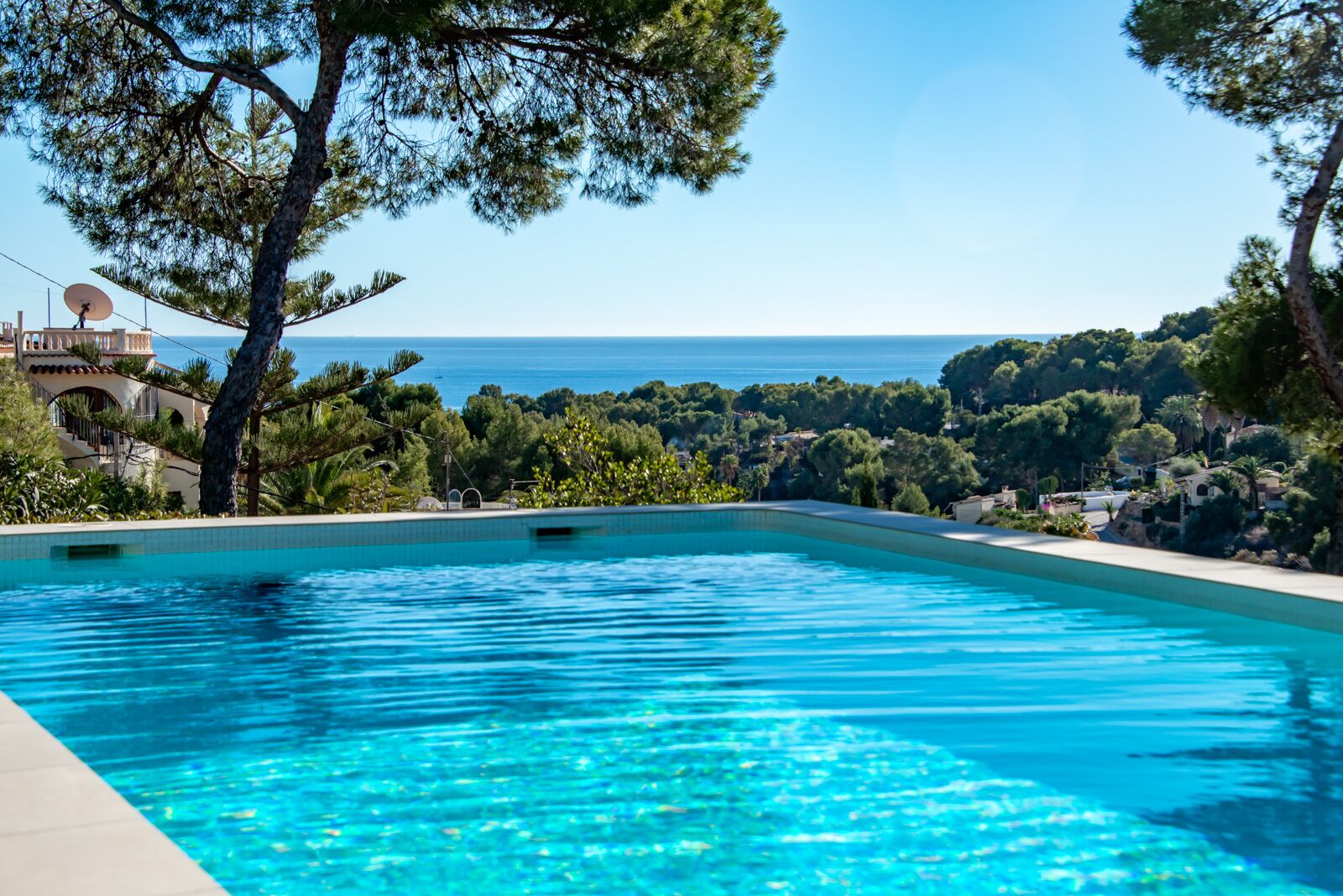 Una piscina con vista despejada al mar y la vegetación circundante.