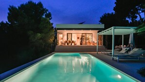 Una casa moderna con piscina, un patio cubierto y un comedor.
