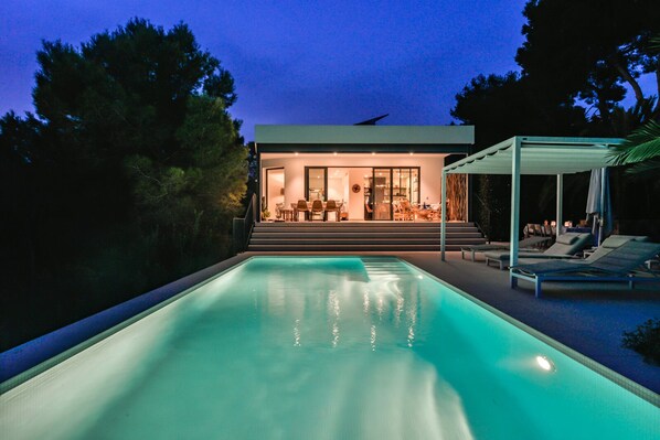 A modern house with a swimming pool, a covered patio, and a dining area.