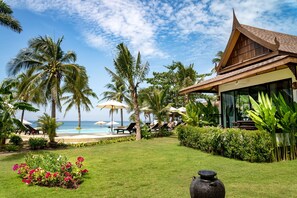 A tropical resort with a pool, palm trees, and a beach view.
