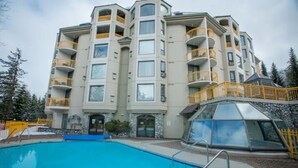 Un hotel de varios pisos con balcones, piscina y una estructura cubierta de vidrio.
