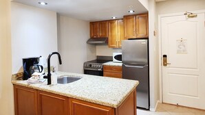 Una cocina compacta con encimera de granito, electrodomésticos de acero inoxidable, armarios de madera e iluminación empotrada.