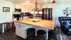A spacious kitchen with a large island, stainless steel appliances, and a black leather chair. - Golf & Ski Townhome in Avon, Colorado (Avon)
