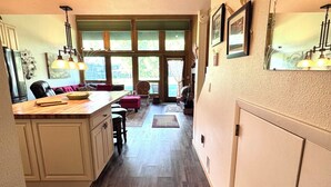 A kitchen with wooden flooring, a dining area with a table and chairs, and a view through large windows. - Golf & Ski Townhome in Avon, Colorado (Avon)