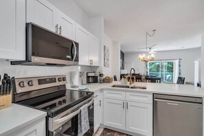 A modern kitchen with white cabinetry, a built-in microwave, an oven, and a dishwasher. - The Charm of Kissimmee (Kissimmee)