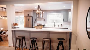 Une cuisine moderne dotée d’un grand îlot central, d’appareils électroménagers en acier inoxydable et de tabourets noirs.