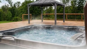 Un bain à remous avec une terrasse en bois et un gazebo en arrière-plan.