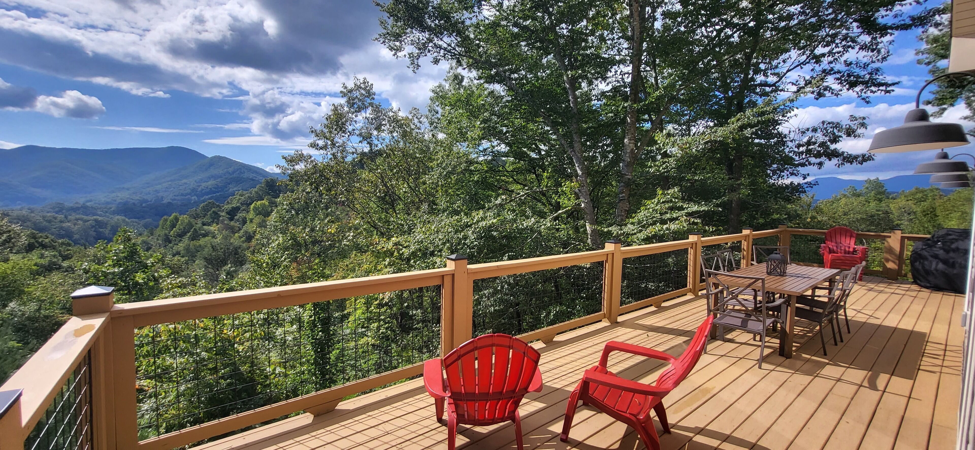 A wooden deck with a table and chairs, overlooking a mountainous landscape.