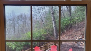 A window with a view of outdoor seating and a sign about no food, down drain, and septic system. - Cozy Mountain Chalet with views, private setting! Near WCU and Castle Ladyhawke  (Cullowhee)