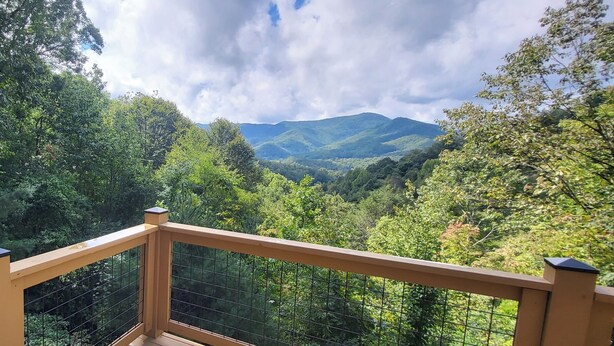 A balcony with a view of a forested valley and distant mountains. - Cozy Mountain Chalet with views, private setting! Near WCU and Castle Ladyhawke  (Cullowhee)
