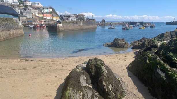 A coastal town with a sandy beach, rocky shoreline, and a harbor with boats. - Sea View House in Cornwall Fishing Village (St Austell)