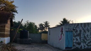 Une cour avec un bassin d’eau, une fresque représentant une sirène et une construction à toit de chaume.