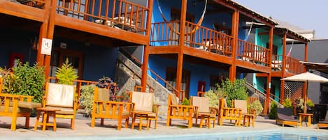 Una piscina al aire libre, sombrillas, sillones reclinables de piscina