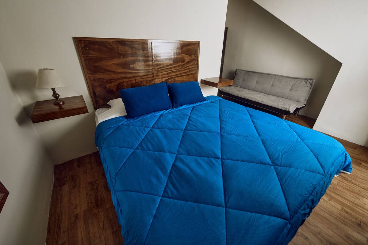 Ein Schlafzimmer mit einem großen Bett, einem Nachttisch, einer Ablage und einem Sofa.