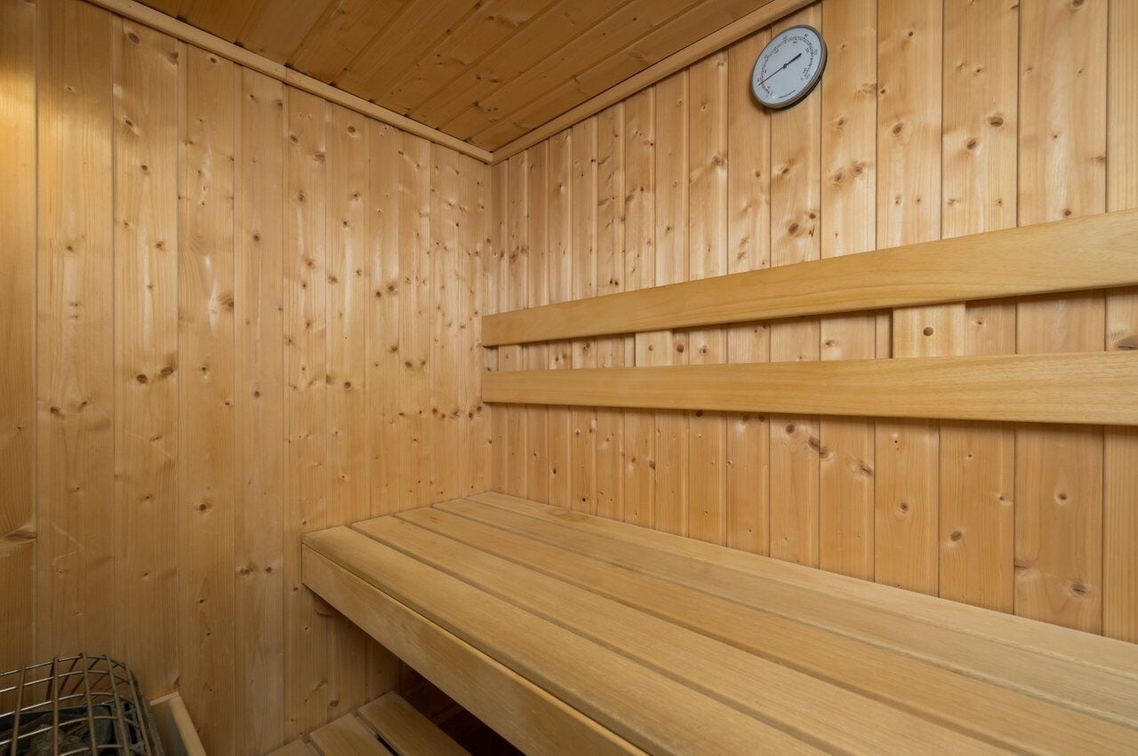 A sauna with wooden benches and a wall-mounted thermometer.