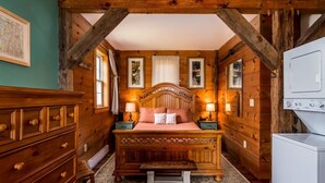 Een knus slaapkamer met een houten bed, nachtkastjes, een dressoir en een ingebouwde wasmachine.