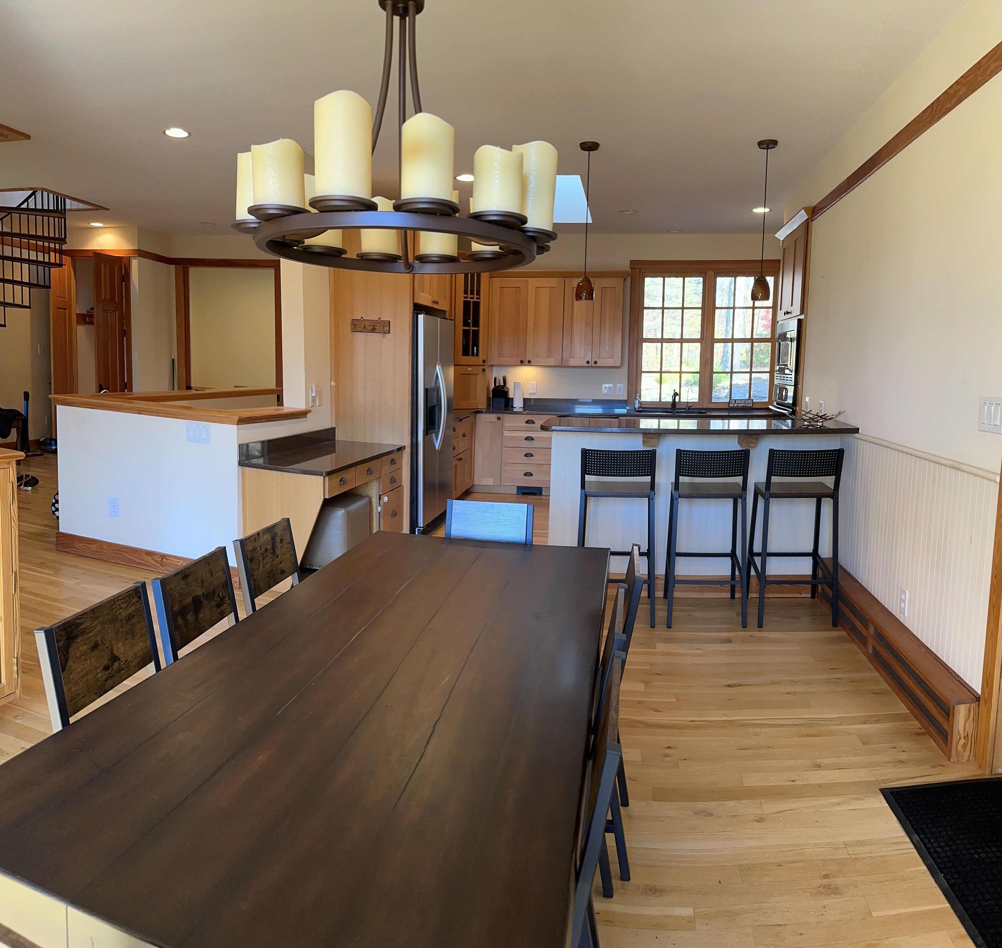 A spacious kitchen with wooden cabinets, a central island, and a dining area with a large table and chairs.