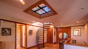 Une pièce spacieuse dotée d’une lucarne, d’un plancher en bois, d’un escalier en colimaçon et de portes en bois.