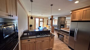 Une cuisine moderne avec des meubles en bois, un réfrigérateur en acier inoxydable et une cuisinière à gaz intégrée.