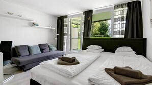 A hotel room with a bed, a sofa, a desk, and a window with curtains. - Studio Apartment "Schmetterling" Near the Slopes with Shared Pool and Wi-Fi (Sankt Englmar)