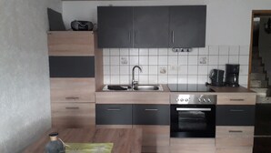 A modern kitchen with dark cabinets, a sink, a stove, and a coffee maker. - Holiday Apartment "Ferienwohnung Köppl" with Terrace (LAM)