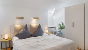 A modern bedroom with a bed, bedside lamps, a nightstand, a wardrobe, and a skylight. - Holiday Apartment "Anette" with Mountain View, Balcony & Wi-Fi (Garmisch-Partenkirchen)