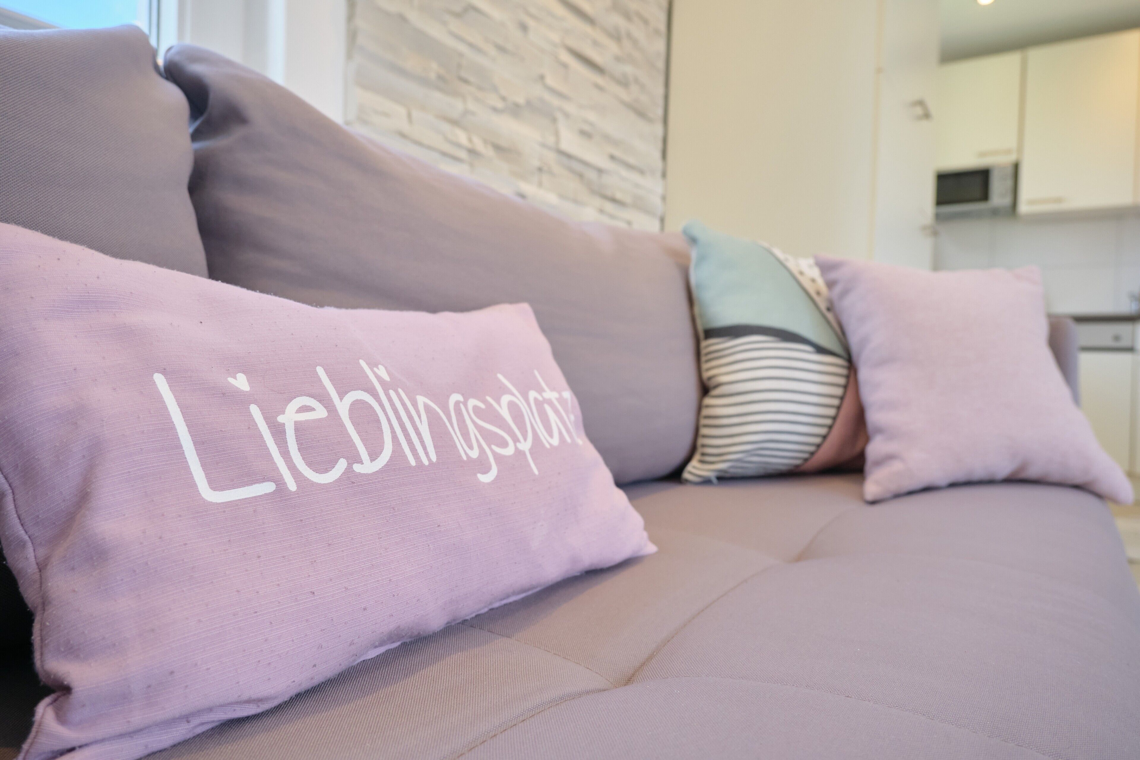 Ein Sofa mit einem Kissen, auf dem 'Lieblingsplatz' steht.