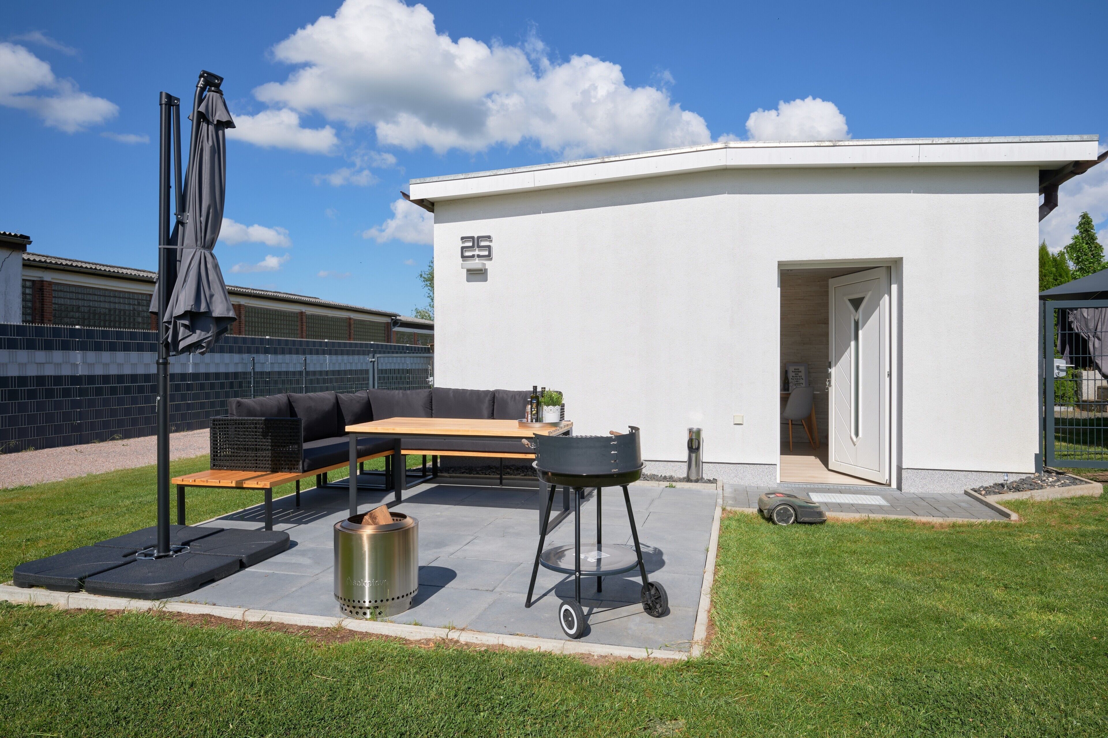 A patio with a black grill, a wooden table, and a black sofa.