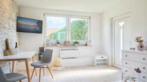 Une cuisine moderne dotée d’une grande fenêtre, de meubles blancs et d’un coin repas avec des chaises grises.