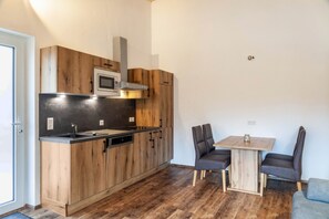 Una cocina compacta con armarios de madera, un microondas y una zona de comedor con dos sillas y una mesa.