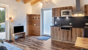 Une cuisine moderne avec des meubles en bois, un four à micro-ondes encastré et un plan de travail noir.