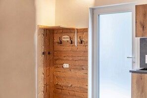 A wooden wall with a 'Willkommen' sign, a door, and a small kitchen area.